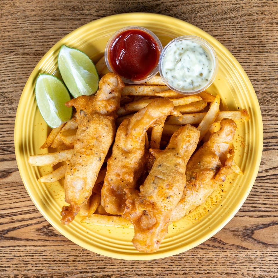 Fairweather's fish and chips with limes, ketchup, and tartar sauce on a yellow plate.